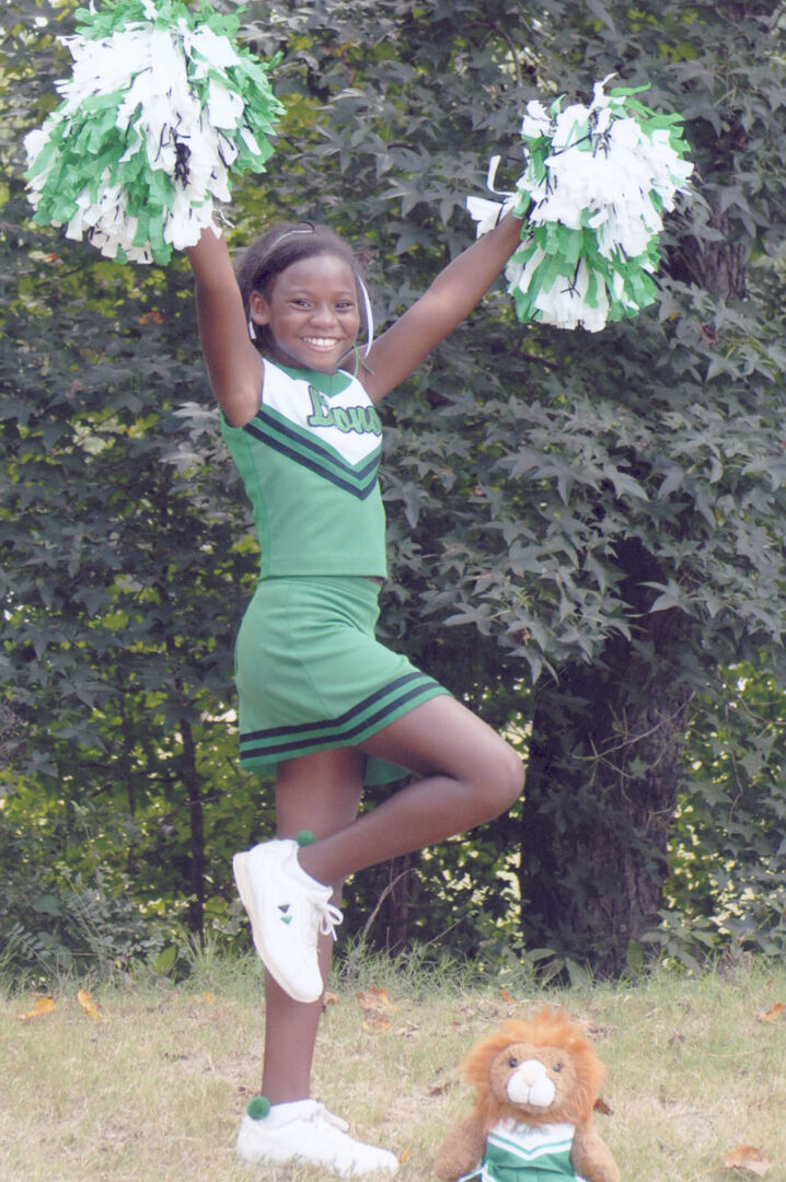 A young girl in green and white cheerleader outfit.